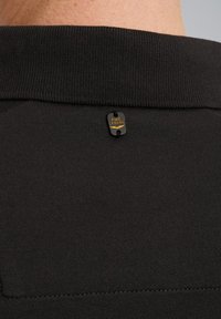Zwarte katoenen T-shirt met een gestructureerde kraag en een klein metalen label met de inscriptie "PME LEGEND" op de achterkant.