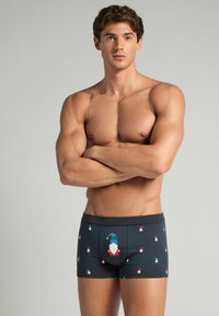 Námořnické modré boxerky s potiskem skřítků v několika barvách; mají přední kapsu a elastický pas. Hladký povrch.