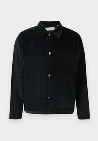 Sort fløjl jakke med krave, forlommer og sølvknapper. Har lodrette ribber i stofstrukturen. Enkel design.