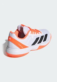 Hvid sports sko med orange accenter og sorte striber. Mesh-overdel, polstret krave og struktureret gummisål for greb. Modelnavn: COURTFLASH.