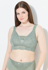 Lace bralette in gedempt groen met een golvende zoom, een v-hals ontwerp en brede bandjes, gecombineerd met bijpassende hoge taille brief.