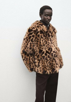 Chaqueta de piel sintética con estampado de leopardo marrón, con una textura gruesa y suave, con cierre de cremallera al frente, que se lleva sobre pantalones oscuros. Fondo liso.