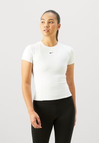 Camiseta atlética blanca de manga corta con escote redondo, que presenta un pequeño logo negro de Nike en el pecho. Diseño suave y ajustado.