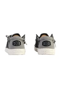 Zapatos de lona grises con un acabado texturizado, que cuentan con una suela salpicada de blanco y un logo negro "HEY DUDE" en la parte posterior. Diseño de cordones simple.