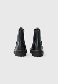 Black leather ankle boots with a textured finish, elastic side panels, and a thick rubber sole featuring a tread pattern.
