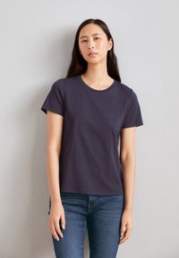 Granatowa, krótko rękawowa koszulka z bawełny z okrągłym dekoltem i luźnym krojem, połączona z dopasowanymi dżinsami.