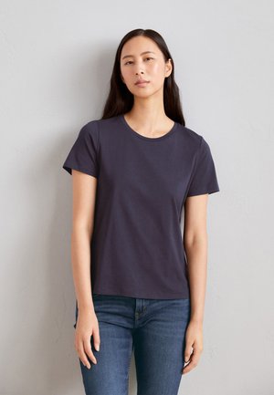 T-shirt blu navy a maniche corte in cotone con scollo rotondo e vestibilità comoda, abbinata a jeans aderenti.