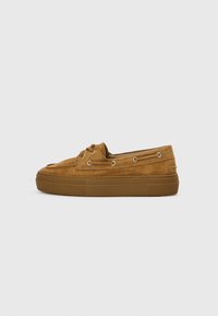 Suede loafers in a light brown color with a low platform sole, rounded toe, and metal eyelets for laces. Textured upper surface.