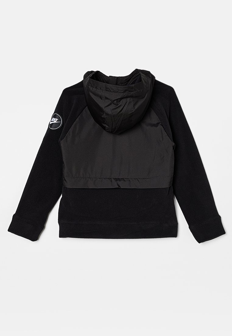 Felpa nera con texture in fleece, caratterizzata da una sezione superiore in tessuto liscio a contrasto, un cappuccio e un logo circolare sulla manica.