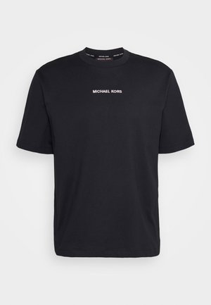 Sort T-shirt med korte ærmer og rund hals, med hvid "MICHAEL KORS" tekst centreret på brystet og matchende logotekst inde i kraven.