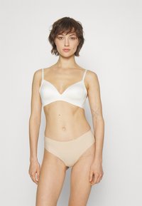 White seamless bra with thin straps and a V-neckline, paired with beige high-waisted briefs. Smooth fabric and minimalist design.