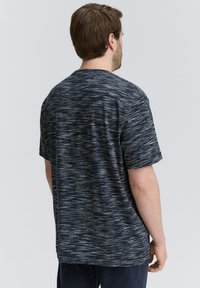 Mørkeblå kortærmet t-shirt med et struktureret, stribet mønster i lysere nuancer. Afslappet pasform, rund hals, blødt stof og minimal detaljer.
