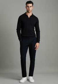 Pulover tricotat negru cu guler, asortat cu pantaloni slim-fit de culoare bleu închis și adidași albi. Design simplu cu o textură netedă.