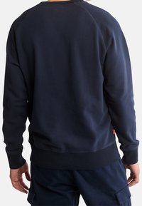 Námořnická modrá mikina s kulatým výstřihem, ribovanými manžetami a lemem. Vyrobena z měkké látky, s hladkým povrchem a jednoduchým designem.