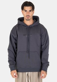 Felpa con cappuccio in cotone grigio, dotata di tasca a marsupio, cappuccio regolabile con lacci e stampa del logo frontale. Presenta polsini e orlo a costine.