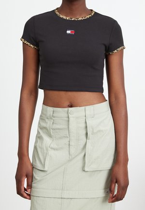 Czarna krótka koszulka z lamówką w panterkę i małym logo Tommy Jeans, noszona z jasnobeżową spódnicą z wysokim stanem i przednimi kieszeniami.