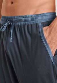 Donkergrijze sportshorts van een lichtgewicht stof, met een elastische tailleband, verstelbaar trekkoord en zijzakken met contrasterende lichtblauwe afwerking.