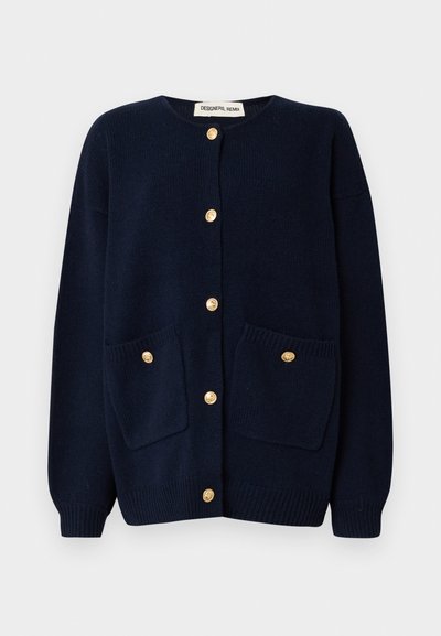 Cárdigan azul marino con cuello redondo, puños acanalados y dos bolsillos delanteros. Incluye cierres con botones dorados y un tejido de punto texturizado.