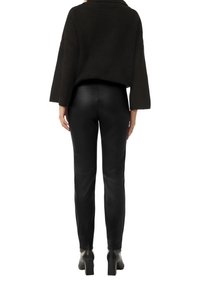 Czarny dzianinowy sweter z szerokimi rękawami, zestawiony z dopasowanymi czarnymi skórzanymi spodniami. Całość uzupełniają czarne botki na obcasie.