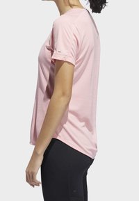 Ljusrosa träningströja med korta ärmar, rund halslinje och slät textur, tillsammans med svarta tights som sitter tätt.