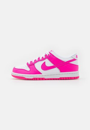 Baskets basses Nike blanche et rose vif avec lacets, bout perforé et Swoosh marqué sur fond blanc.