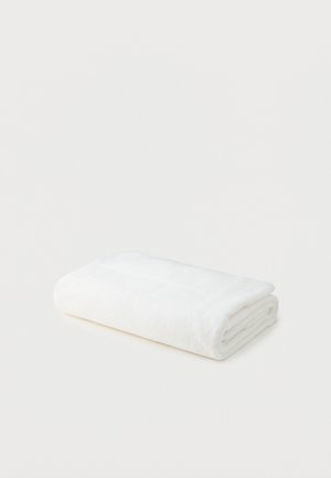 Asciugamano da bagno bianco in cotone piegato, posizionato su uno sfondo bianco semplice.