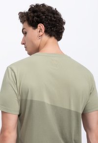 T-shirt in cotone verde chiaro con un motivo a blocchi di colore orizzontali, scollatura rotonda e logo a forbici sottile sul retro.
