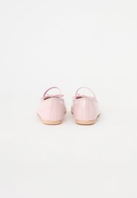 Ballerines en cuir verni rose avec de petites brides arrière et un détail en nœud à l'avant, présentant une texture lisse et une semelle fine.