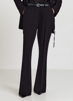 Schwarze maßgeschneiderte Hose mit ausgestelltem Schnitt, glatter Textur und tailliertem Bund. Kombiniert mit einem schwarzen Gürtel mit silberner Schnalle.