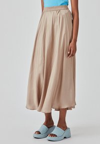 Lett, beige midi-nederdel med elastisk talje, flydende fald og glat tekstur. Kombinationen med lyseblå åbne wedges.