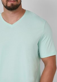 Mintgroene V-hals T-shirt van zacht materiaal. Voorzien van een klein, subtiel logo op de borst en korte mouwen met een relaxte fit.