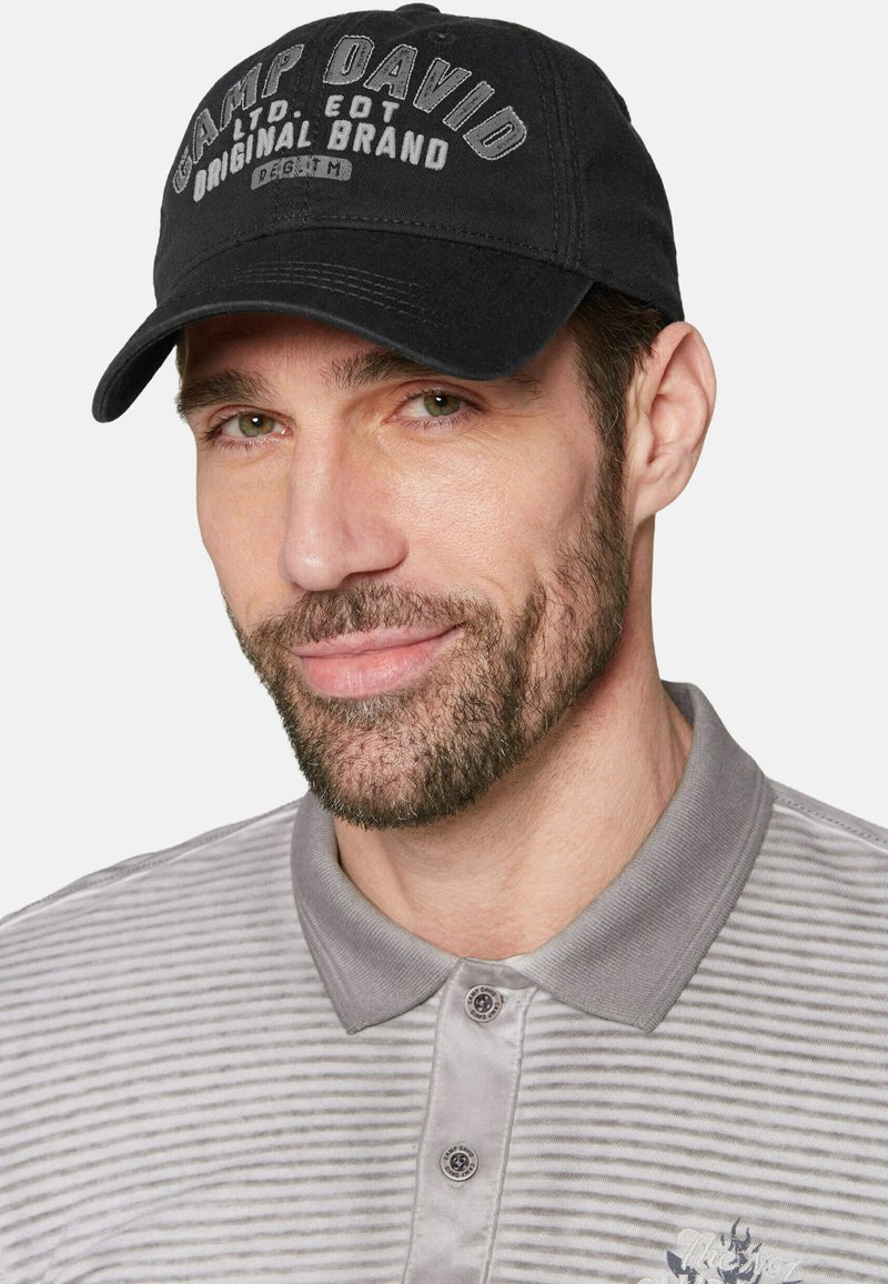 Schwarze Mütze mit dem Text "CAMP DAVID", aus Baumwolle, mit gebogenem Schirm. Grau gestreiftes Poloshirt mit Button-Down-Kragen und besticktem Detail.