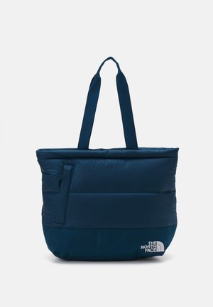 Sac cabas matelassé bleu marine avec double poignée, poche avant zippée et logo "The North Face" en bas à droite.