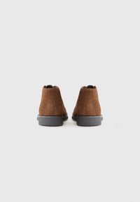 Brown suede ankle boots with a smooth gray rubber sole and a rounded toe. The design features a low cut and subtle seam detailing.