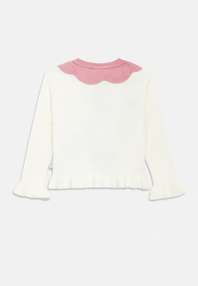 Beli pulover z roza valovitim ovratnikom, rebrastimi manšetami in nabrano spodnjico. Mehka tekstura z dolgimi rokavi in zadnjim dizajnom.