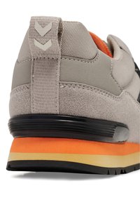 Athletic shoe with gray suede and mesh upper, orange midsole, black rubber outsole, and a rear pull tab featuring a chevron design.
