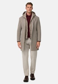 Cappotto di lana grigia con cappuccio, indossato sopra una camicia color granata. Abbinato a pantaloni beige chiaro e scarpe stringate marroni. Design semplice e vestibilità su misura.