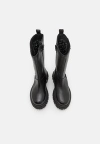 Bottines en cuir noir avec une surface texturée, bout rond, zips latéraux et semelles en caoutchouc épaisses. L'intérieur présente une doublure à motifs.