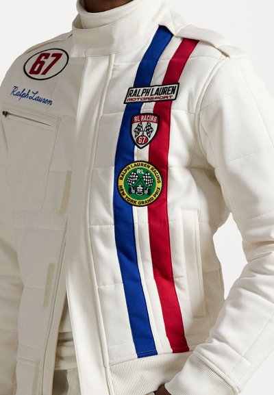 White quilted racing jacket with red and blue stripes, featuring multiple patches, including "Ralph Lauren" and badges. Zippered pocket on side.