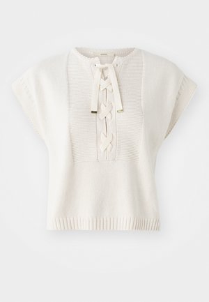 Top curto de malha branca com mangas curtas e decote redondo, apresentando um frente com corda de laços entrelaçados e variações de textura sutis.