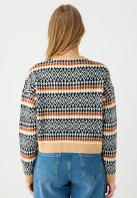 Breisweater met een geometrisch diamanten patroon in zwart, wit, oranje en beige. Kort ontwerp met geribbelde manchetten en zoom.