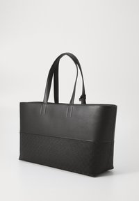 Černá taška přes rameno s hladkým koženým vrškem a texturovanou spodní částí s embosovaným vzorem. Dva odolné popruhy dotvářejí design.