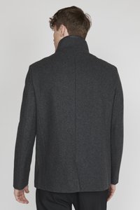 Dunkelgrauer Wollüberzieher mit hohem Kragen, gerader Schnittführung und minimalistischem Design. Strukturierter Stoff, flache Nahtdetails und keine sichtbaren Verschlüsse.