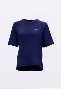 Teget plava muška majica kratkih rukava s okruglim izrezom, izrađena od glatkog materijala, s malim zelenim logotipom na lijevoj strani prsa i asimetričnim rubom.