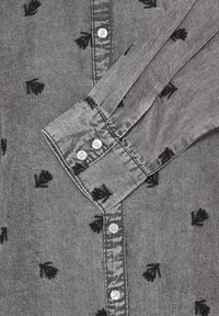 Cămașă gri cu nasturi, dintr-un material moale, cu modele brodate de frunze negre, guler standard și nasturi asemănători perlelor.