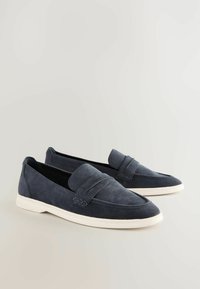 Navy suede loafers with a structured design, featuring a prominent seam and leather accents, set on a white rubber sole.