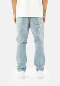 Lyseblå denimjeans med en afslappet pasform, smalle læg, to baglommer og en let falmning. Båret med hvide sneakers.