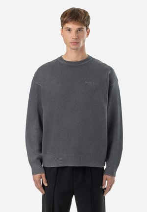 Maglione grigio a maglia con scollatura rotonda e spalle scese. Presenta un tessuto strutturato e un logo discreto sul petto. Vestibilità ampia.