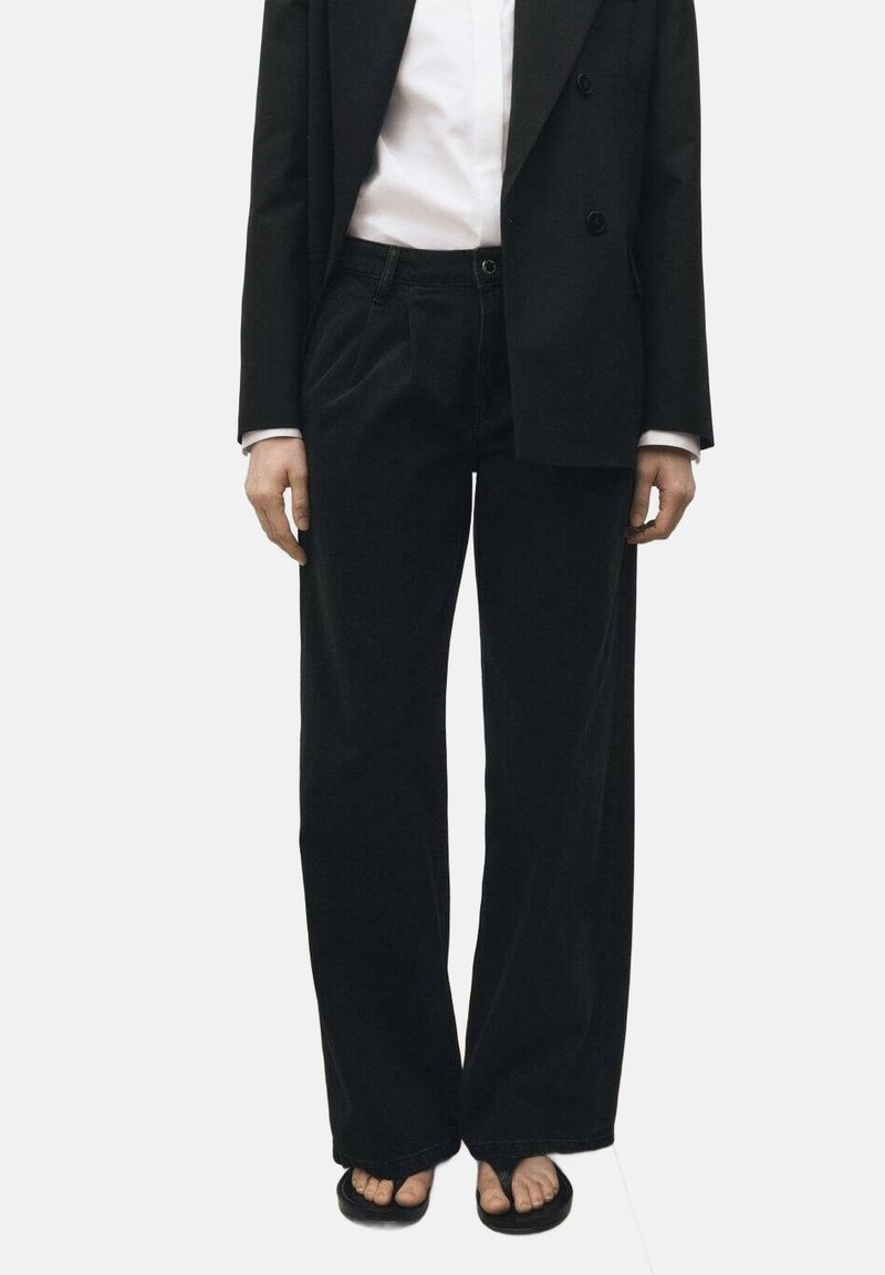 Črne široke hlače iz mehkega bombažnega materiala z teksturirano površino, z sprednjimi žepi in zadrgo.