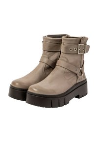 Bottes chelsea en cuir beige avec une sangle et une fermeture à boucle, dotées d'une semelle plateforme noire épaisse et de détails texturés sur les côtés.